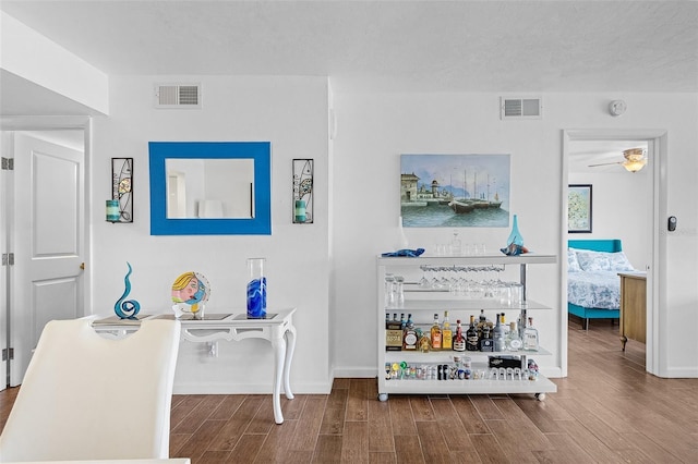 interior space featuring baseboards, ceiling fan, wood finished floors, and visible vents