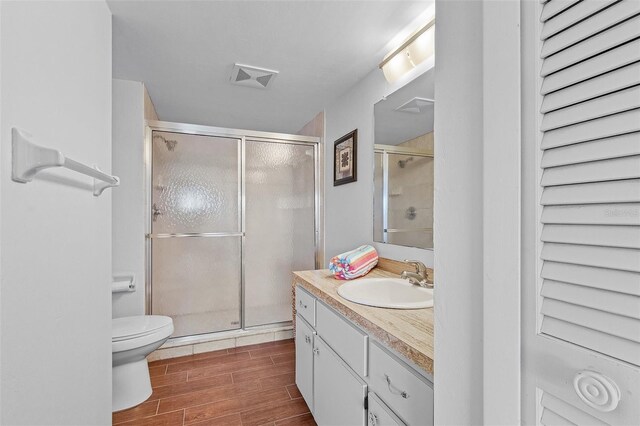 full bathroom featuring visible vents, a shower stall, wood finished floors, vanity, and toilet