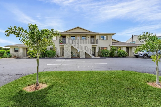 view of front of home with a balcony and a front lawn