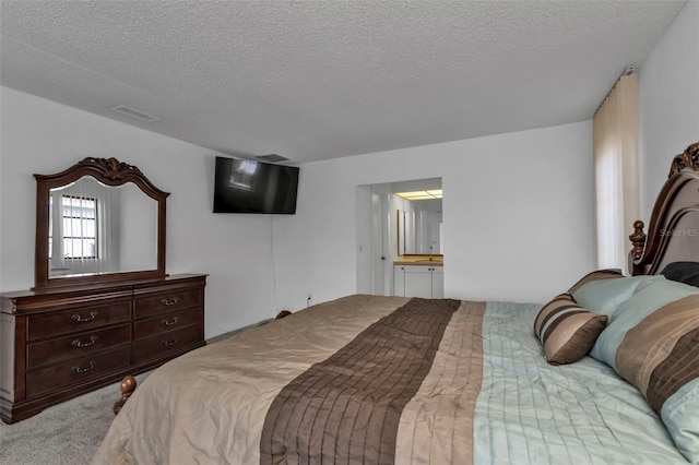 carpeted bedroom featuring a textured ceiling and ensuite bath