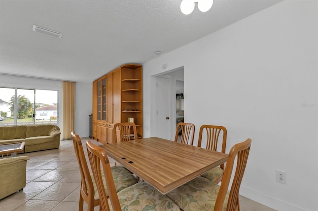 tiled dining room featuring a textured ceiling