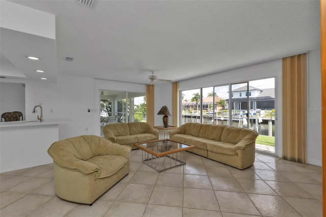 tiled living room featuring a water view and sink