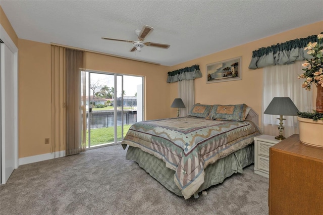 carpeted bedroom featuring a textured ceiling, a water view, ceiling fan, and access to exterior