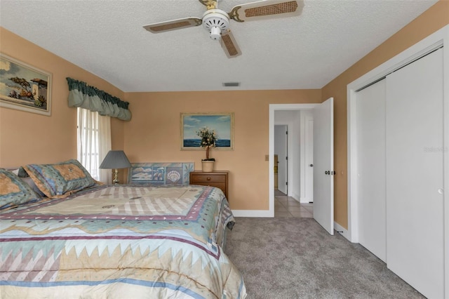 carpeted bedroom featuring ceiling fan, a textured ceiling, and a closet