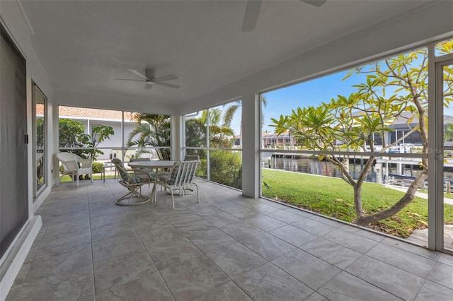 unfurnished sunroom featuring a water view, ceiling fan, and a healthy amount of sunlight