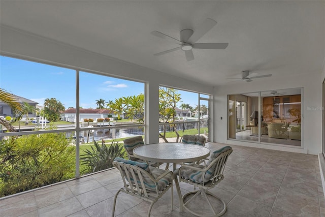 sunroom with a water view and ceiling fan