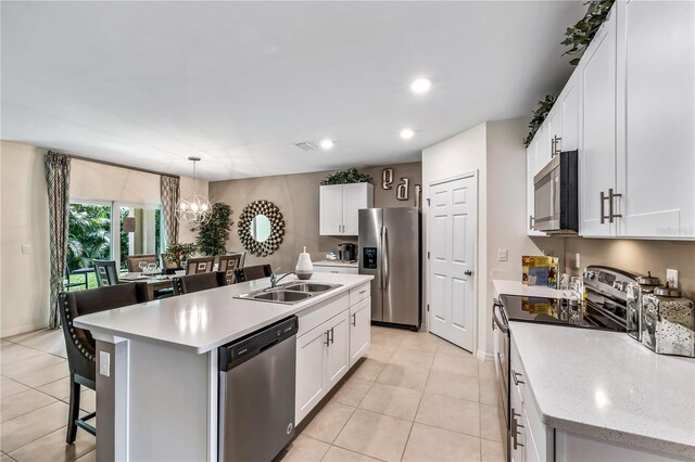 kitchen with sink, hanging light fixtures, a kitchen island with sink, white cabinets, and appliances with stainless steel finishes