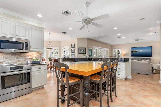 kitchen featuring pendant lighting, white cabinets, stainless steel appliances, decorative backsplash, and light tile patterned flooring