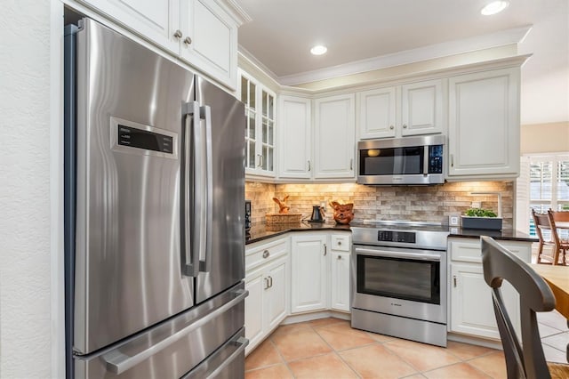 kitchen featuring white cabinets, tasteful backsplash, light tile patterned floors, and stainless steel appliances