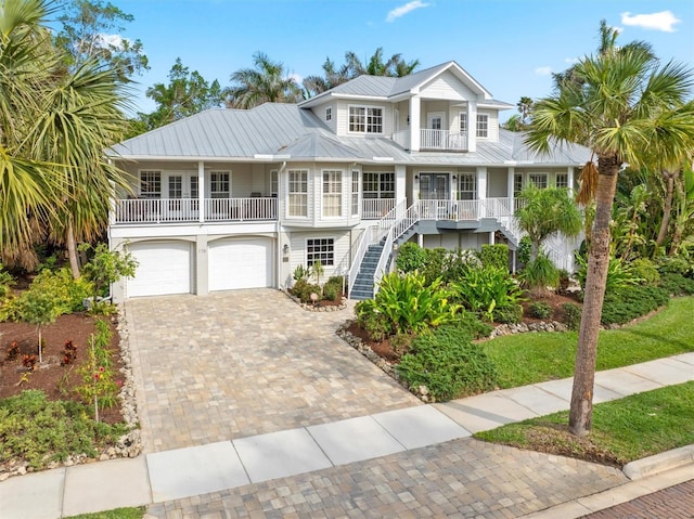 view of front facade featuring a balcony, a garage, covered porch, and french doors