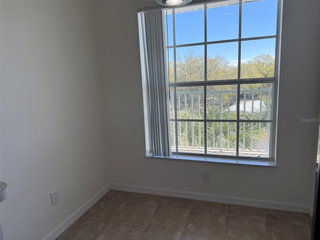 empty room with dark tile patterned floors and baseboards