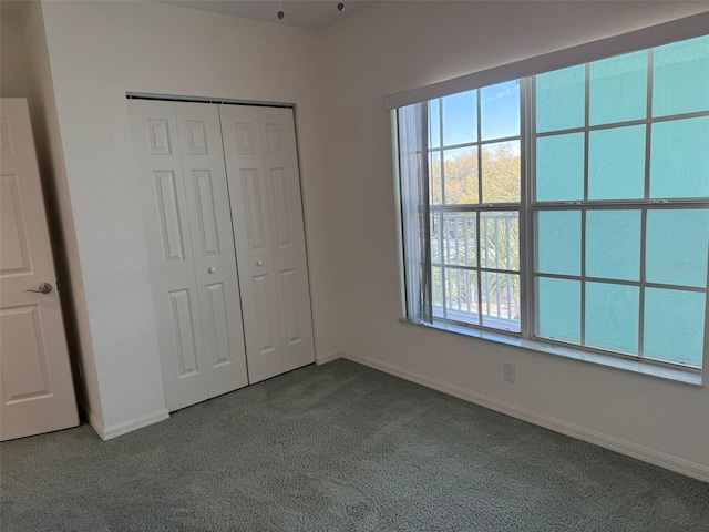 unfurnished bedroom featuring a closet, dark carpet, and baseboards