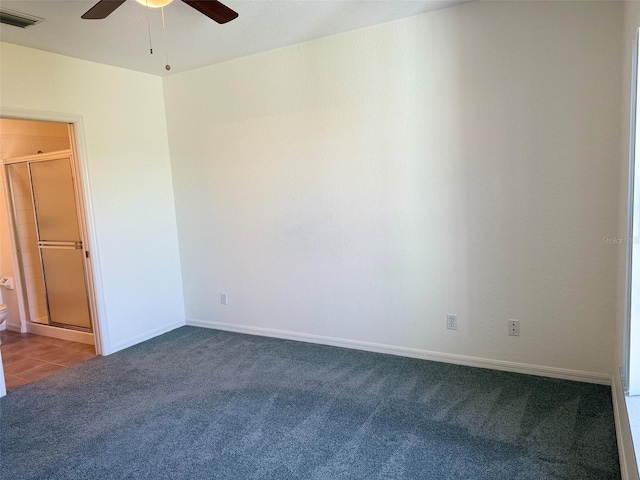 carpeted spare room featuring a ceiling fan, visible vents, and baseboards