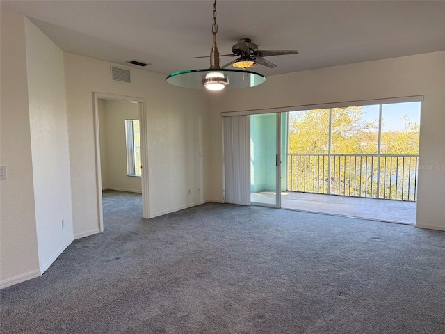 carpeted spare room with a ceiling fan, visible vents, and baseboards