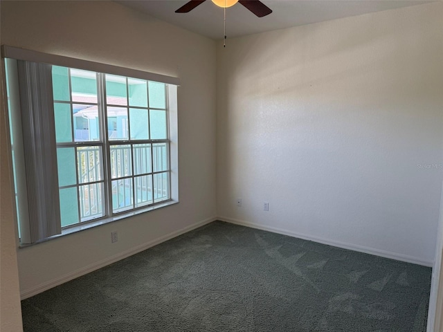 empty room with baseboards, dark carpet, and a ceiling fan