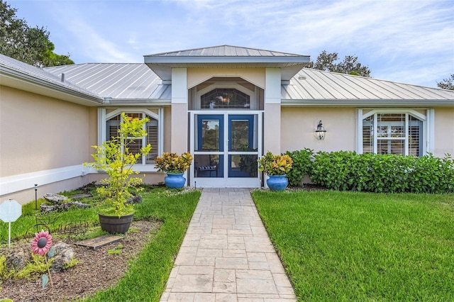 view of exterior entry featuring a lawn