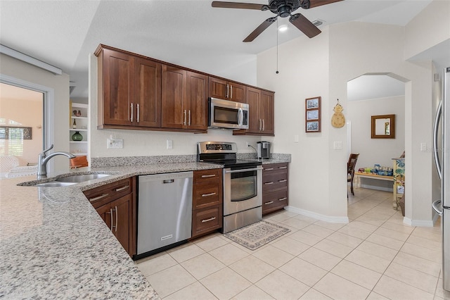 kitchen featuring sink, appliances with stainless steel finishes, light tile patterned floors, light stone countertops, and ceiling fan