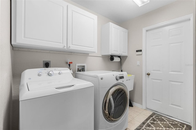 laundry room with washing machine and dryer, light tile patterned flooring, and cabinets