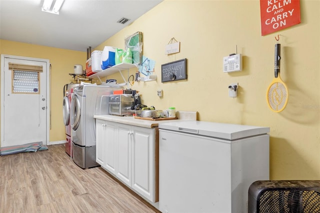 washroom featuring cabinets, light wood-type flooring, and washer and dryer