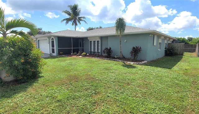 back of property featuring a lawn, a sunroom, and a garage