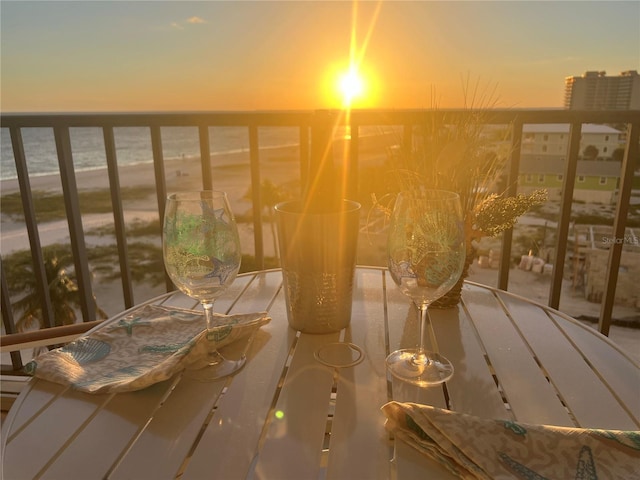 balcony at dusk featuring a water view