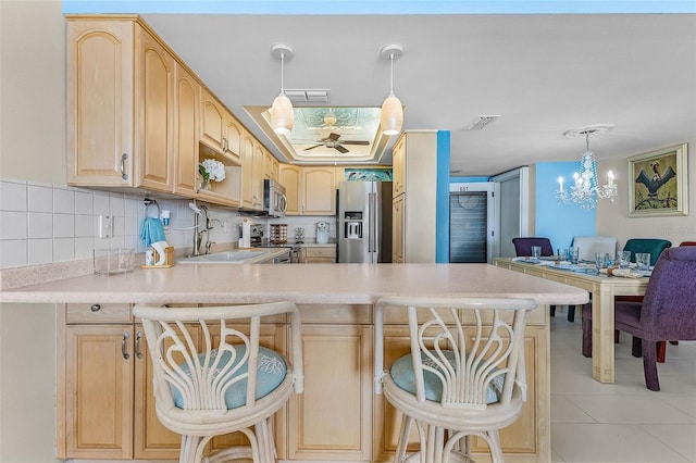 kitchen featuring light brown cabinetry, a kitchen breakfast bar, kitchen peninsula, and stainless steel appliances