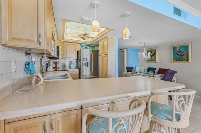 kitchen with appliances with stainless steel finishes, sink, ceiling fan with notable chandelier, decorative backsplash, and light brown cabinets