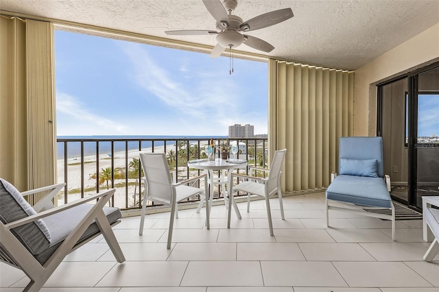 balcony with ceiling fan, a water view, and a beach view