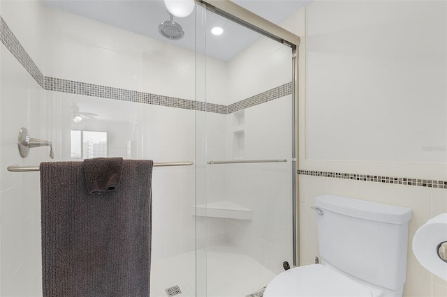 bathroom with toilet, tile walls, an enclosed shower, and ceiling fan