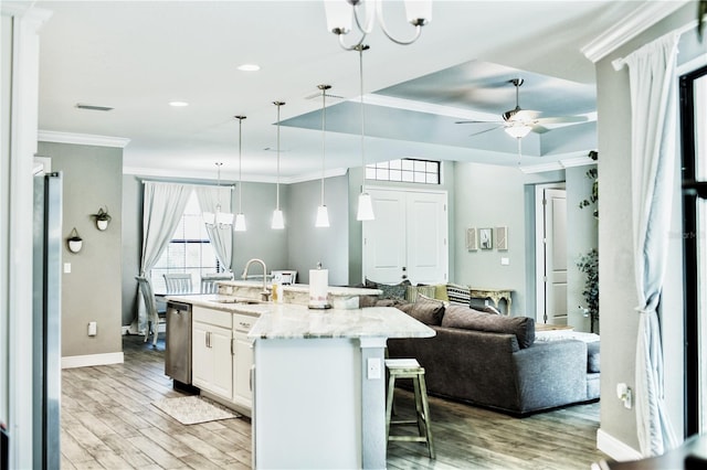 kitchen featuring light stone counters, hardwood / wood-style floors, sink, decorative light fixtures, and a kitchen bar