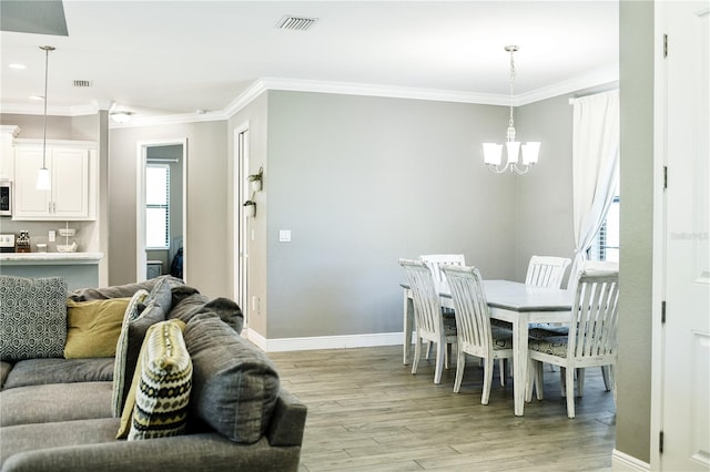 dining room with a notable chandelier, light hardwood / wood-style flooring, and ornamental molding