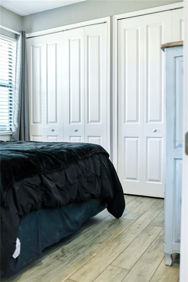 bedroom with two closets and light hardwood / wood-style floors