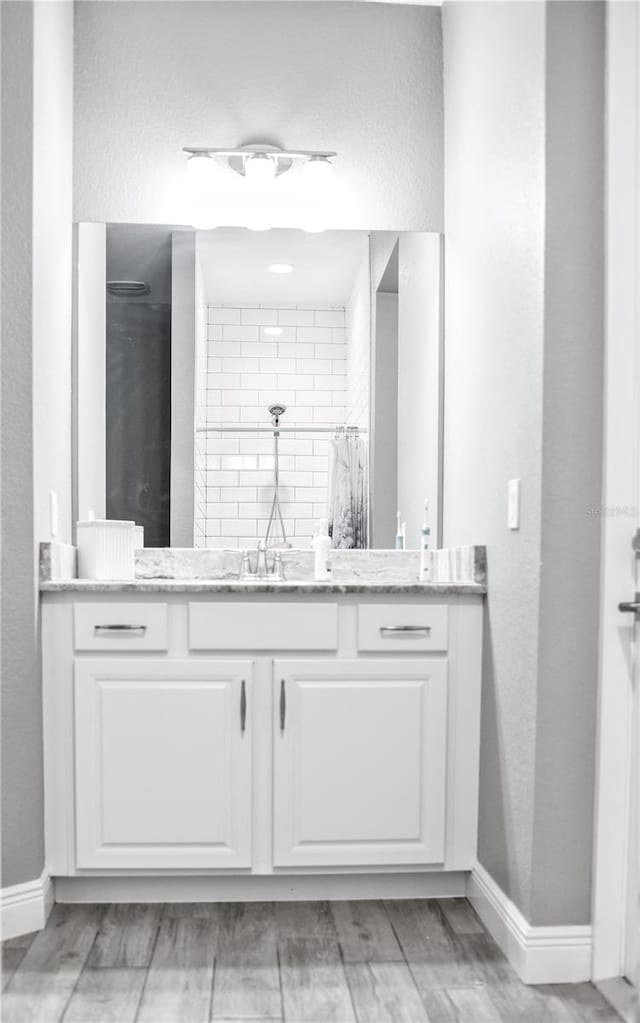 bathroom with a shower with shower curtain, hardwood / wood-style flooring, and vanity