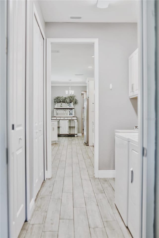 laundry room with light hardwood / wood-style floors, separate washer and dryer, and a notable chandelier