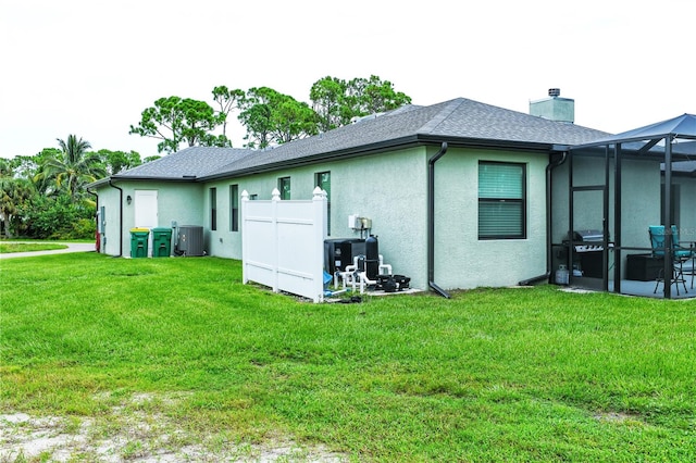 back of house featuring a lanai, cooling unit, and a yard