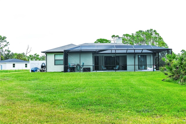 back of property featuring a lanai and a lawn