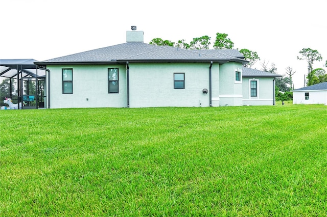 back of property featuring glass enclosure and a yard