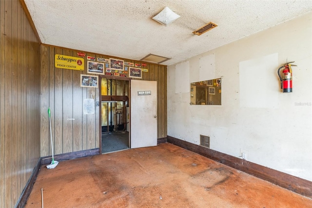 empty room with wooden walls and a textured ceiling