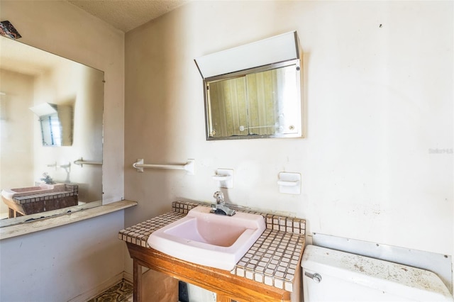 bathroom with a textured ceiling, toilet, and sink