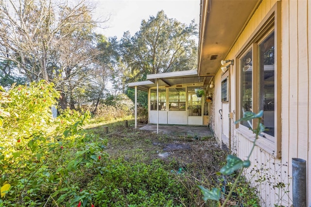 view of yard with a sunroom and a patio