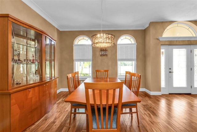 dining room featuring an inviting chandelier, light hardwood / wood-style flooring, and crown molding