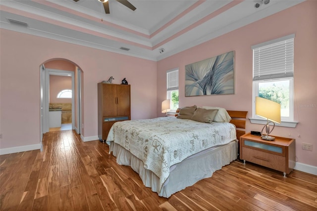 bedroom featuring connected bathroom, ceiling fan, crown molding, and wood-type flooring