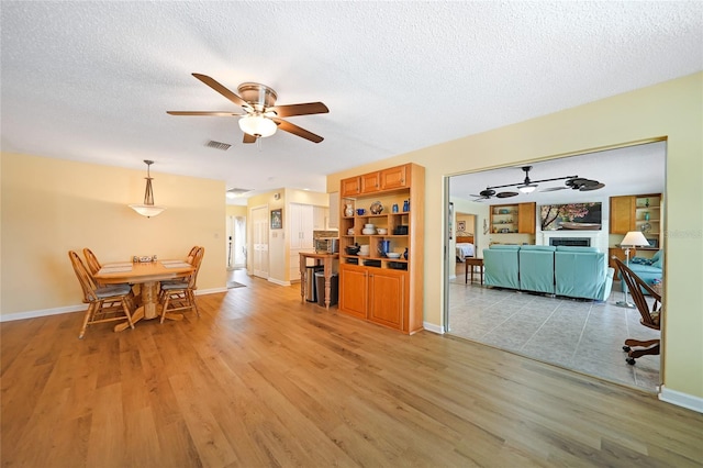 dining room with light hardwood / wood-style flooring, ceiling fan, and a textured ceiling