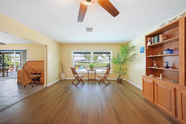 living area featuring a healthy amount of sunlight, a textured ceiling, and hardwood / wood-style flooring