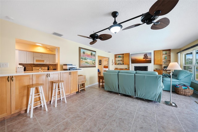 living room featuring ceiling fan, light tile patterned floors, and a textured ceiling