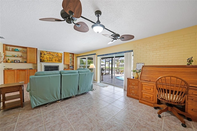 living room featuring brick wall, a textured ceiling, ceiling fan, and light tile patterned flooring