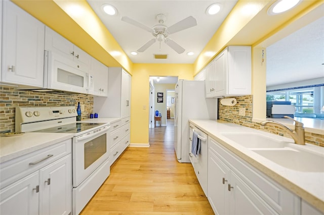 kitchen featuring white cabinets, sink, decorative backsplash, white appliances, and light wood-type flooring