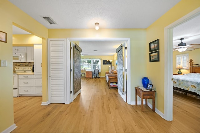 hallway featuring light hardwood / wood-style floors and a textured ceiling