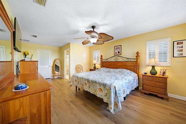 bedroom featuring light hardwood / wood-style flooring, ceiling fan, and a textured ceiling