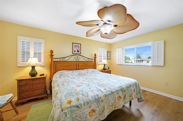 bedroom with light hardwood / wood-style flooring, ceiling fan, and a textured ceiling